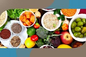 Una composizione dall'alto di alimenti salutari in ciotole, tra cui cereali, legumi, semi, olive verdi, carote, broccoli e frutta fresca, racchiusa in una cornice grafica colorata.